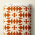 A roll of patterned fabric with a repeating white bird and starburst motif on a warm orange-brown background, shown against a light beige wall. A white label at the top reads CLOUD9.
