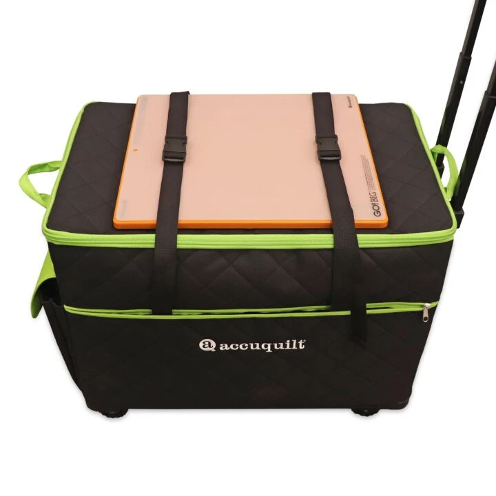 A black quilted rolling storage bag with bright green piping and black straps, shown on a white background with a peach-colored item strapped on top.