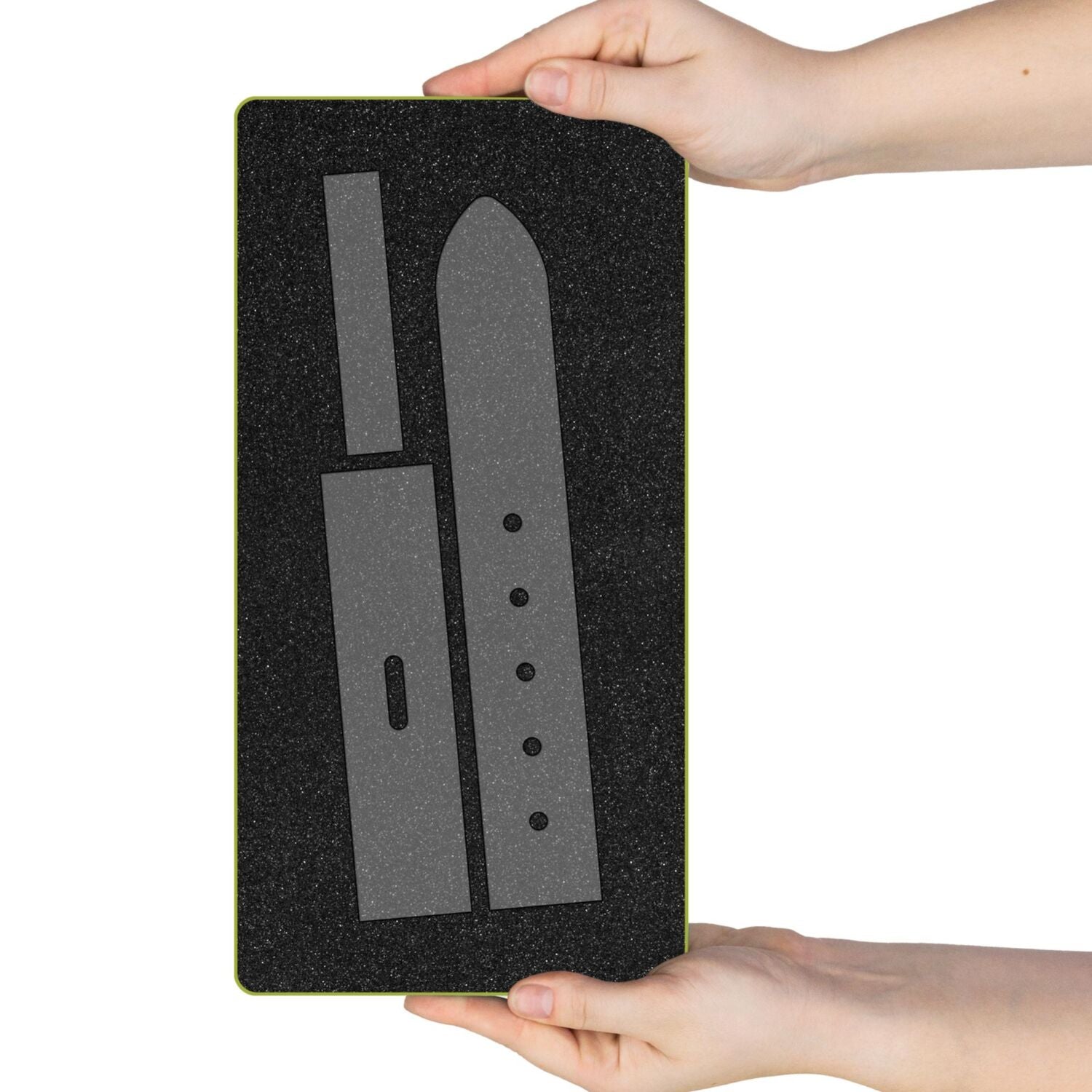 A black textured rectangular mat with a gray strap-shaped template, held by two hands against a white background.