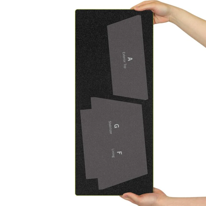 A person holds a black rectangular foam board with three gray letter-shaped foam inserts labeled A, G, and F, shown against a plain white background.