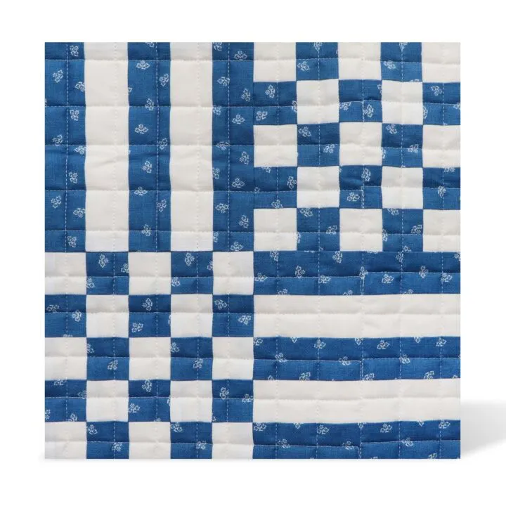 Blue and white checkered quilt with floral patterns on a white background