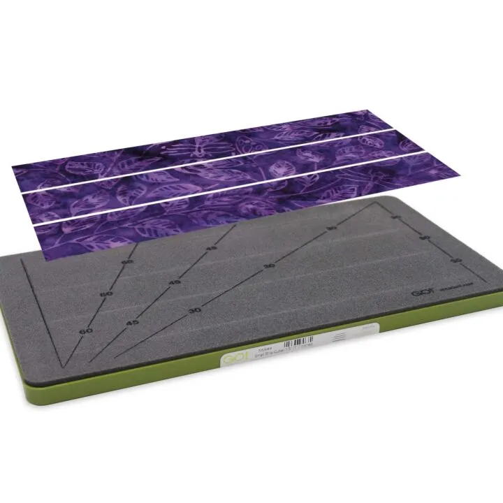 Gray and green cutting mat with purple patterned paper on a white background