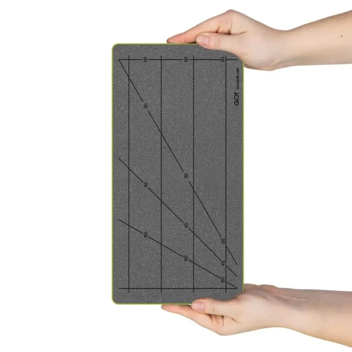 Gray cutting mat with grid lines held by a hand on a white background