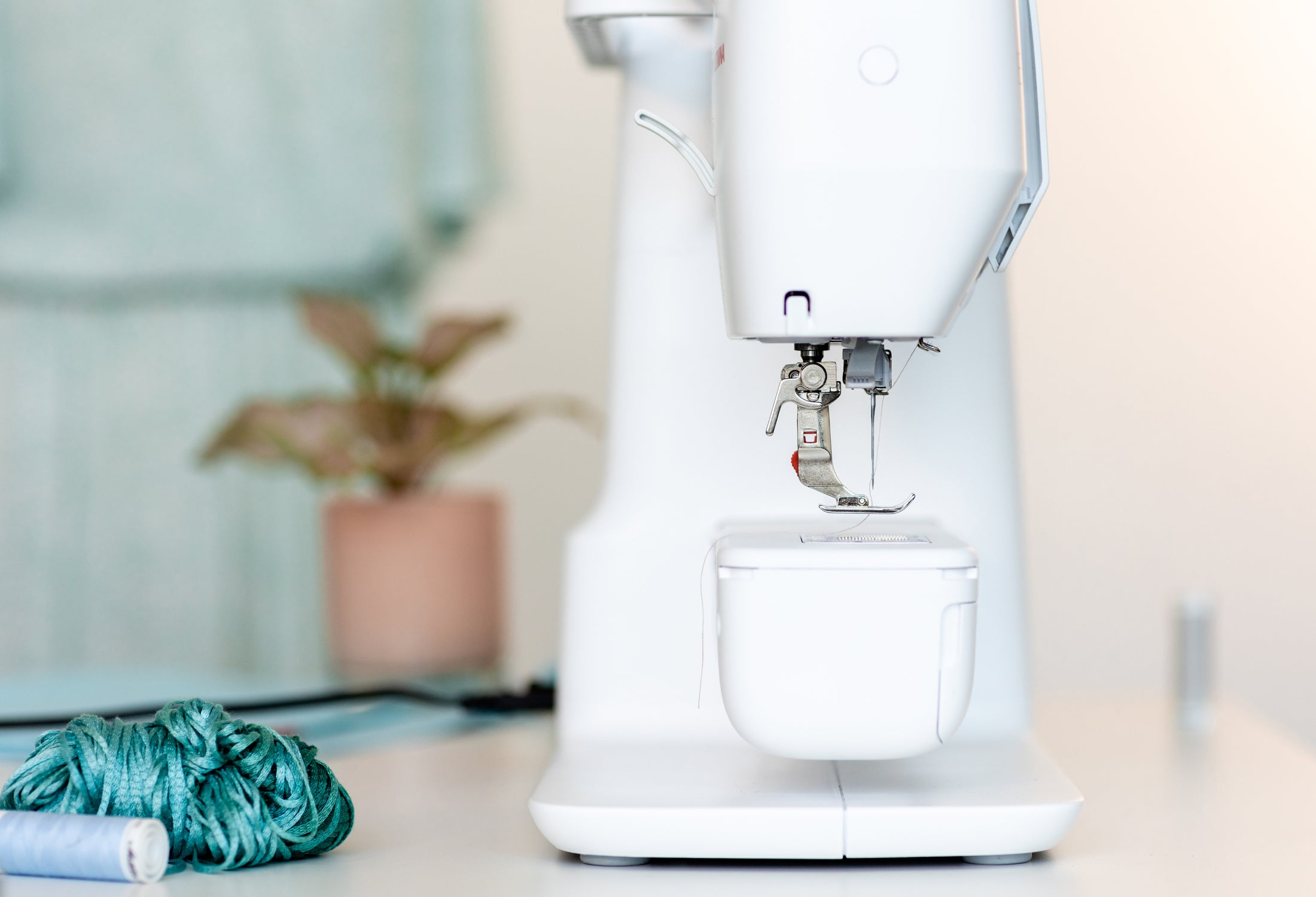 White sewing machine on a light-colored surface with a blurred background