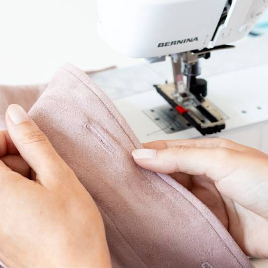 Person using a Bernina sewing machine to sew fabric.
