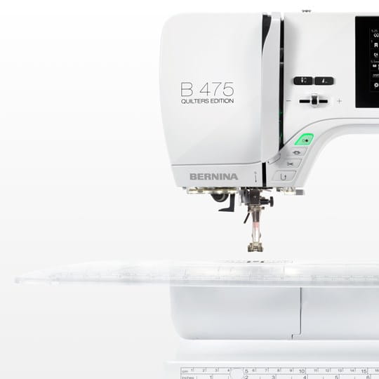 A close-up of a white Bernina B 475 Quilter's Edition sewing machine on a clean white background, showing the brand name, model number, needle area, and part of the transparent presser foot.