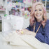Woman with pink hair using a sewing machine in a craft store setting