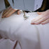 Close-up of hands operating a sewing machine on white fabric
