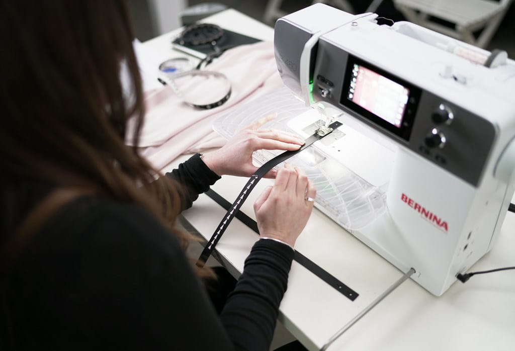 Person using a sewing machine on a table with various items.