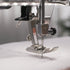 Close-up of a sewing machine needle and foot on a white fabric background