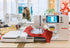 Bernina sewing machine with a red fabric sample on a table in a bright room.