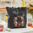 Black tote bag with floral embroidery on a blurred background