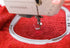 Sewing machine needle stitching on red fabric with 'Bernina' branding.