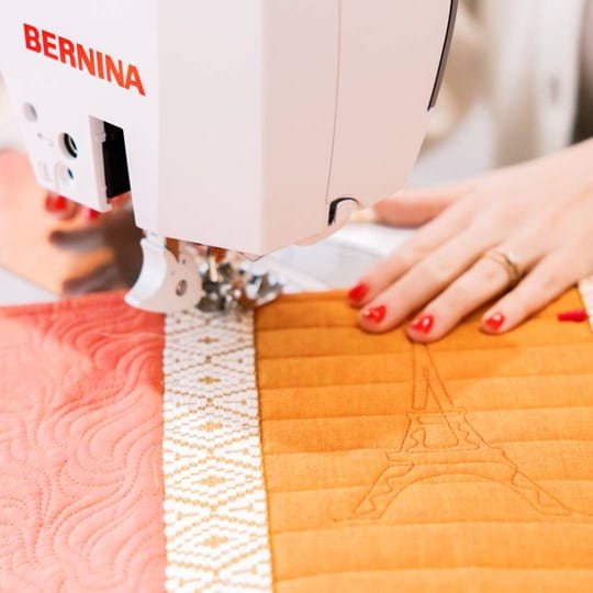 Person using a Bernina sewing machine on a quilt with the Eiffel Tower design.