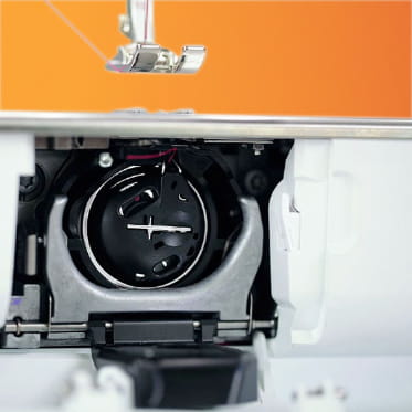 Close-up of a sewing machine needle and bobbin mechanism with an orange background