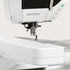 Close-up of a white BERNINA sewing machine showing the needle area, presser foot, and part of the control panel on a light neutral background.
