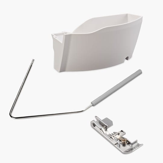 White sewing machine attachment kit with a presser foot, scrap bin, and balance wheel on a white background.