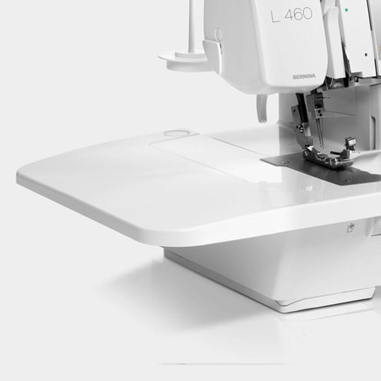 A close-up studio shot of a white sewing machine, showing the upper arm, needle area, and flat bed against a clean white background.