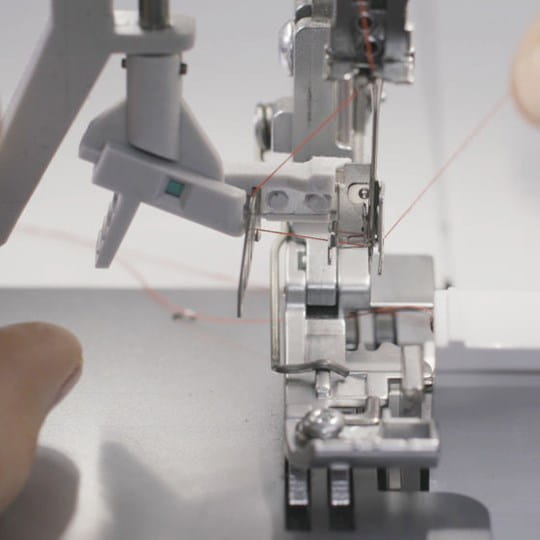 Close-up of a sewing machine needle and mechanism on a white background