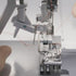 Close-up of a sewing machine needle and mechanism on a white background
