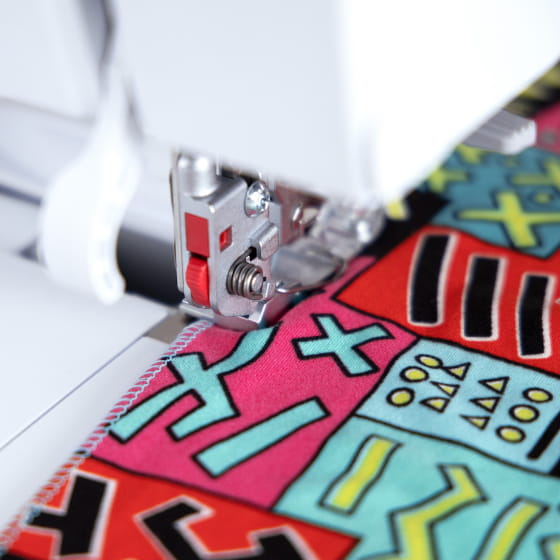 Close-up of a sewing machine needle stitching colorful fabric with geometric patterns.
