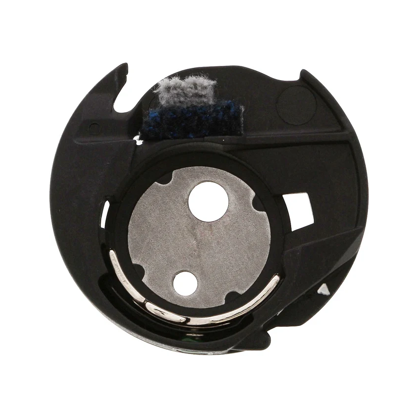 A circular black bobbin case with a brushed silver metal center, a curved silver metal band, and a dark blue textured brush on the top edge, isolated on a white background.