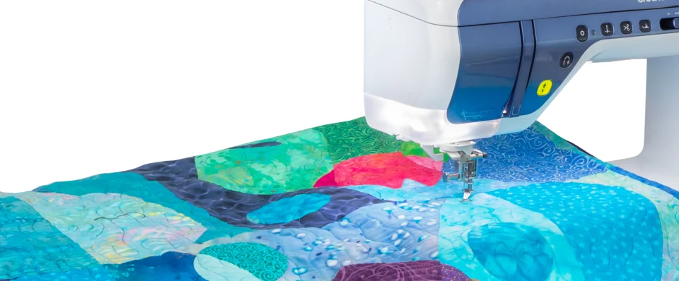 Embroidery machine stitching a colorful fabric design on a white background