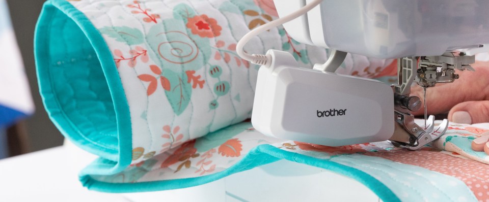 Sewing machine with a floral fabric roll on a white background