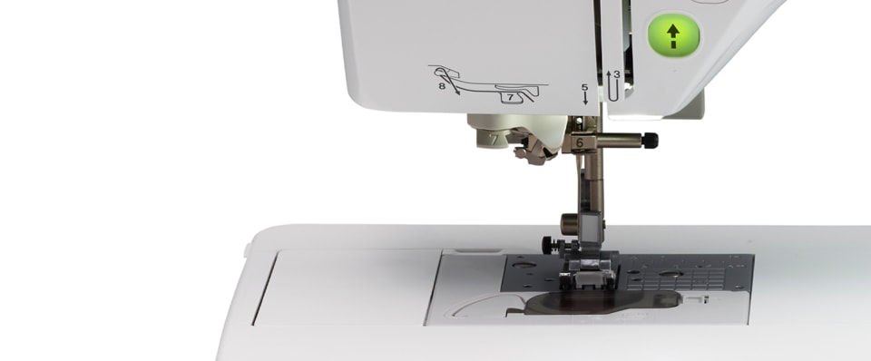Close-up of a white sewing machine showing the needle area, press foot, and part of the upper housing with a small green button on a white background.
