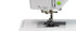 Close-up of a white sewing machine showing the needle area, press foot, and part of the upper housing with a small green button on a white background.