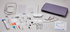 A complete embroidery machine kit laid out on a light gray background, including a lavender zippered case, white machine body, multiple bobbins, thread spools, needles, scissors, tools, grids, and instruction manuals.
