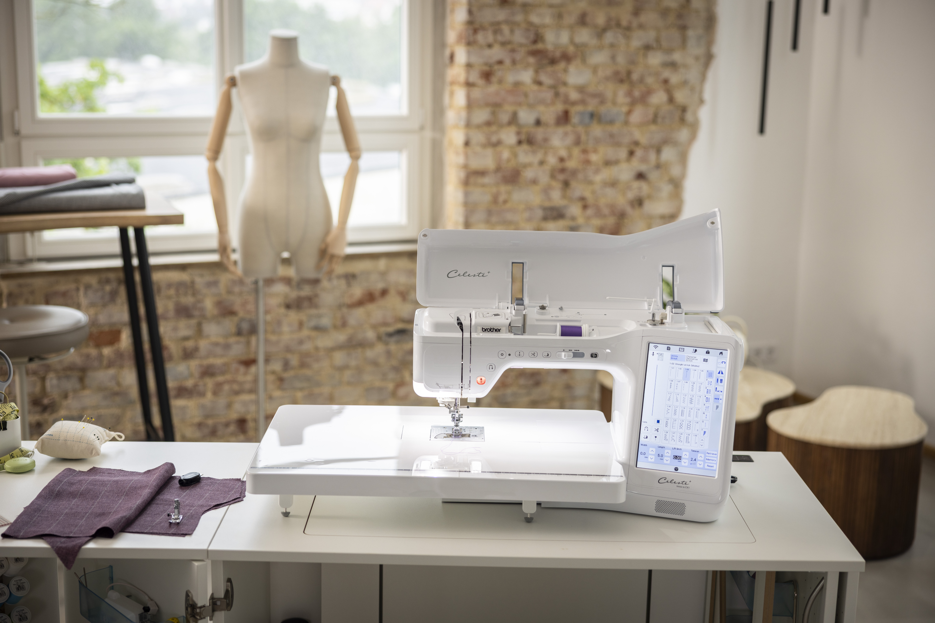 Cordless sewing machine on a table with a mannequin and window in the background