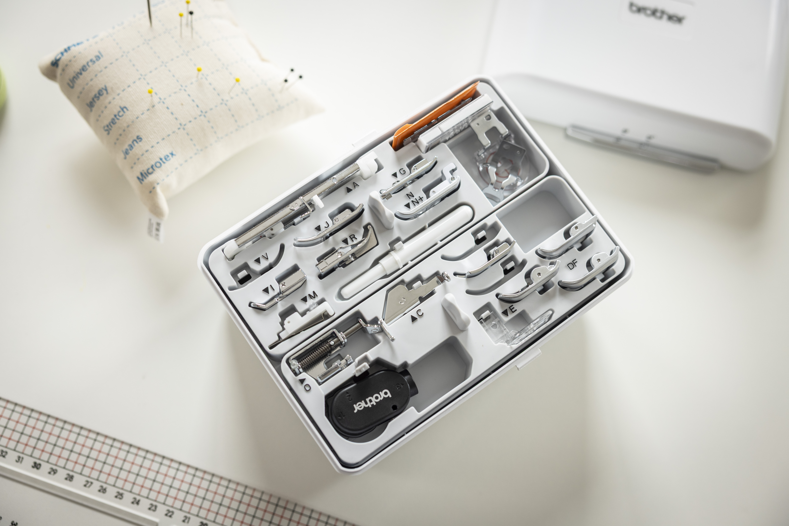 Set of sewing machine accessories in a box on a white surface