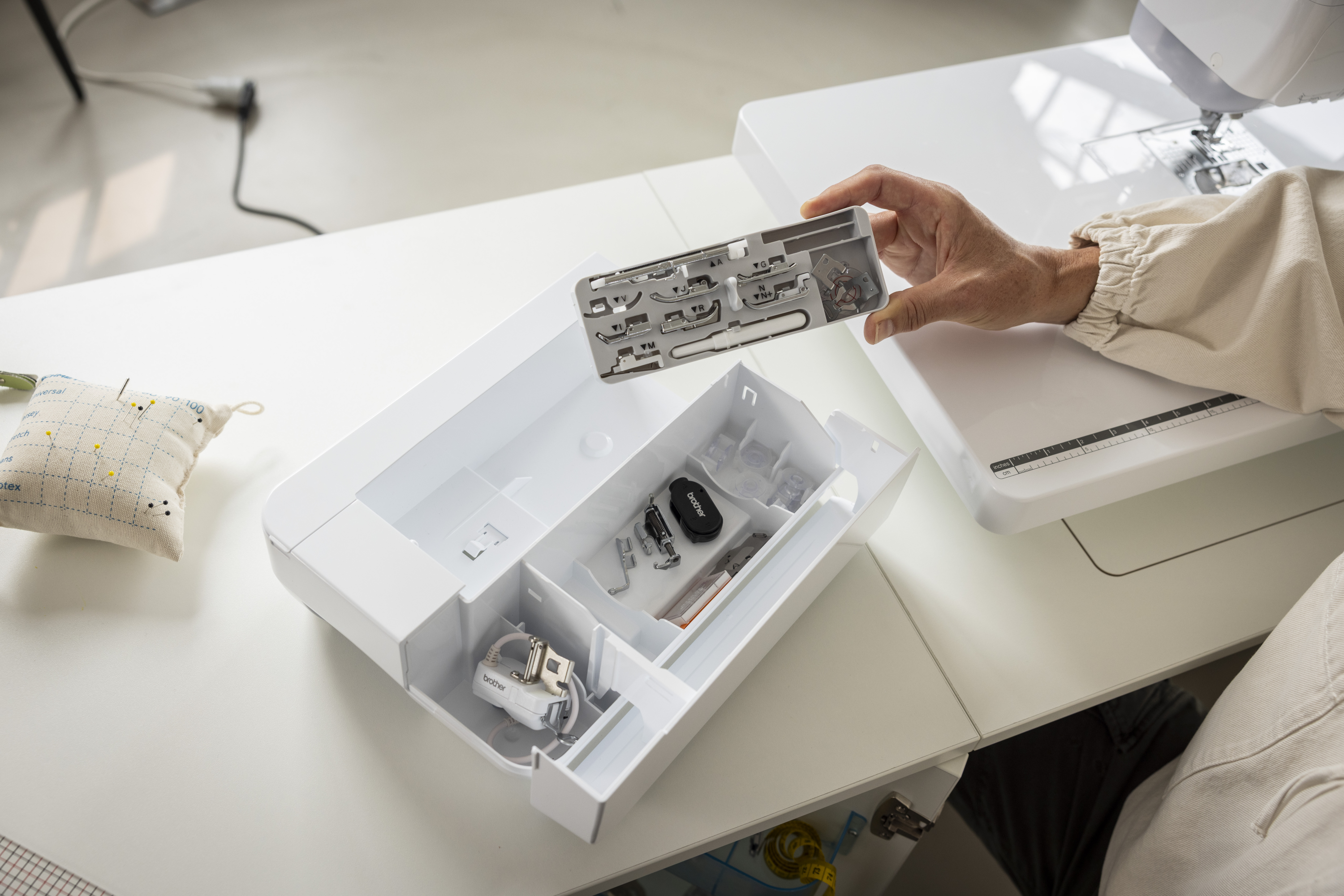 Set of sewing machine accessories in a box on a white surface