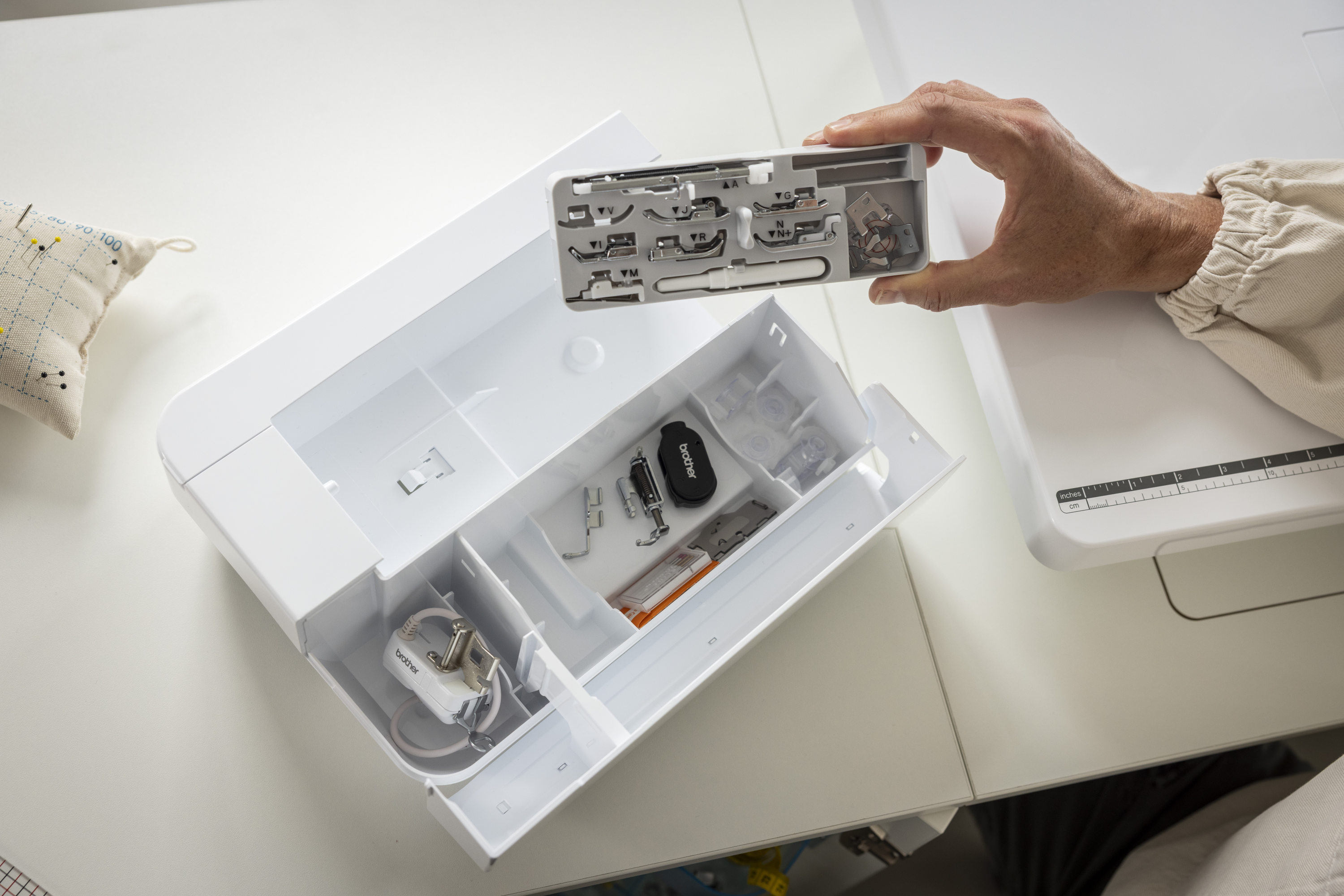 Set of sewing machine accessories in a box on a white surface