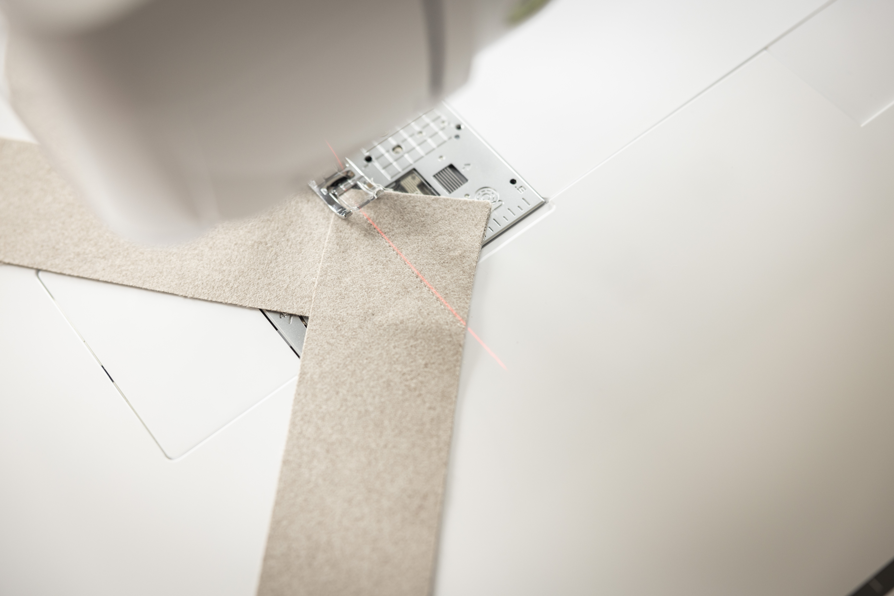 Close-up of a sewing machine needle and fabric on a white background