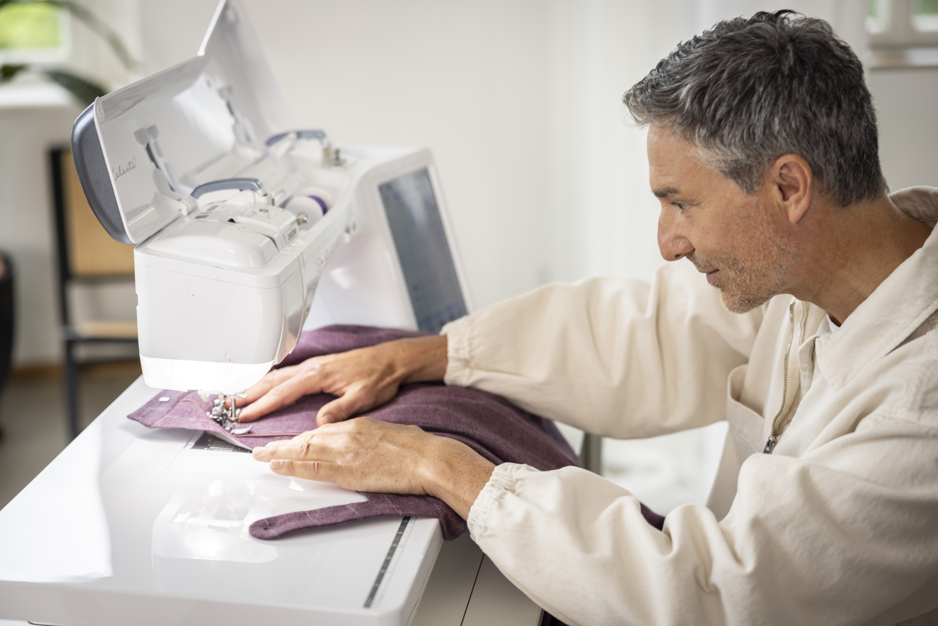 Man working on a sewing machine with fabric in a home setting