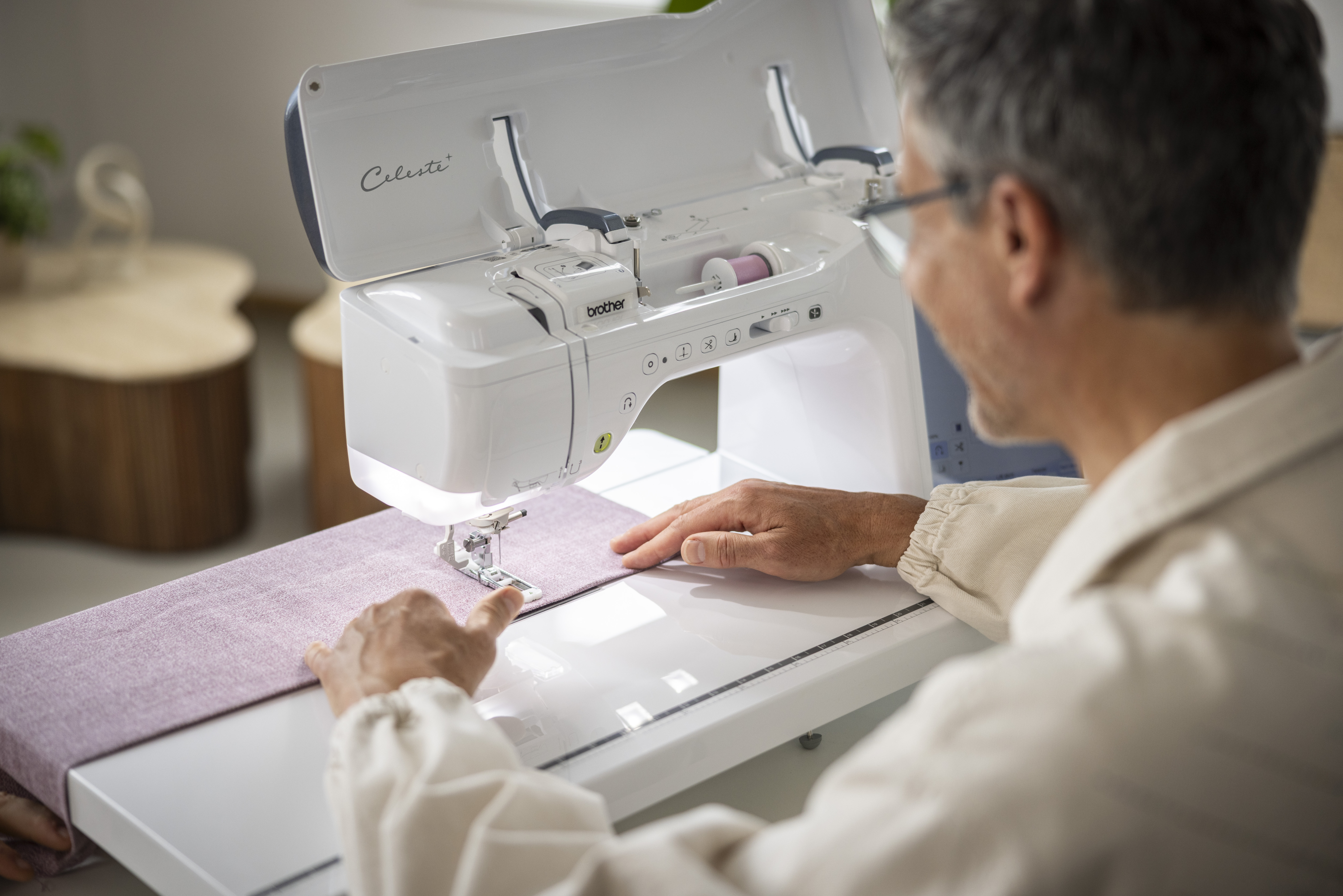 Person using a sewing machine with a focus on the machine and the person's hands.