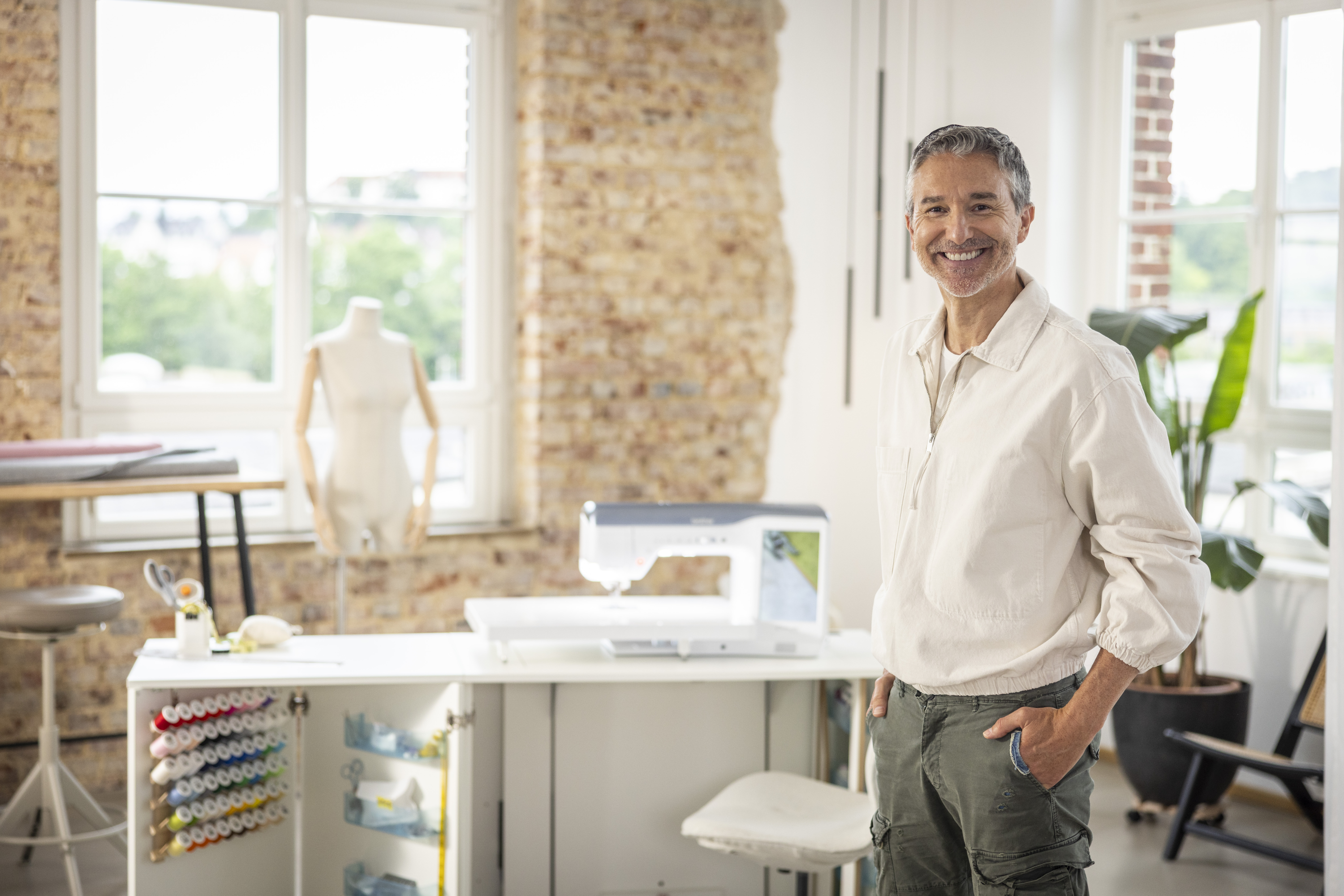 Man standing in a bright, modern office space with large windows.