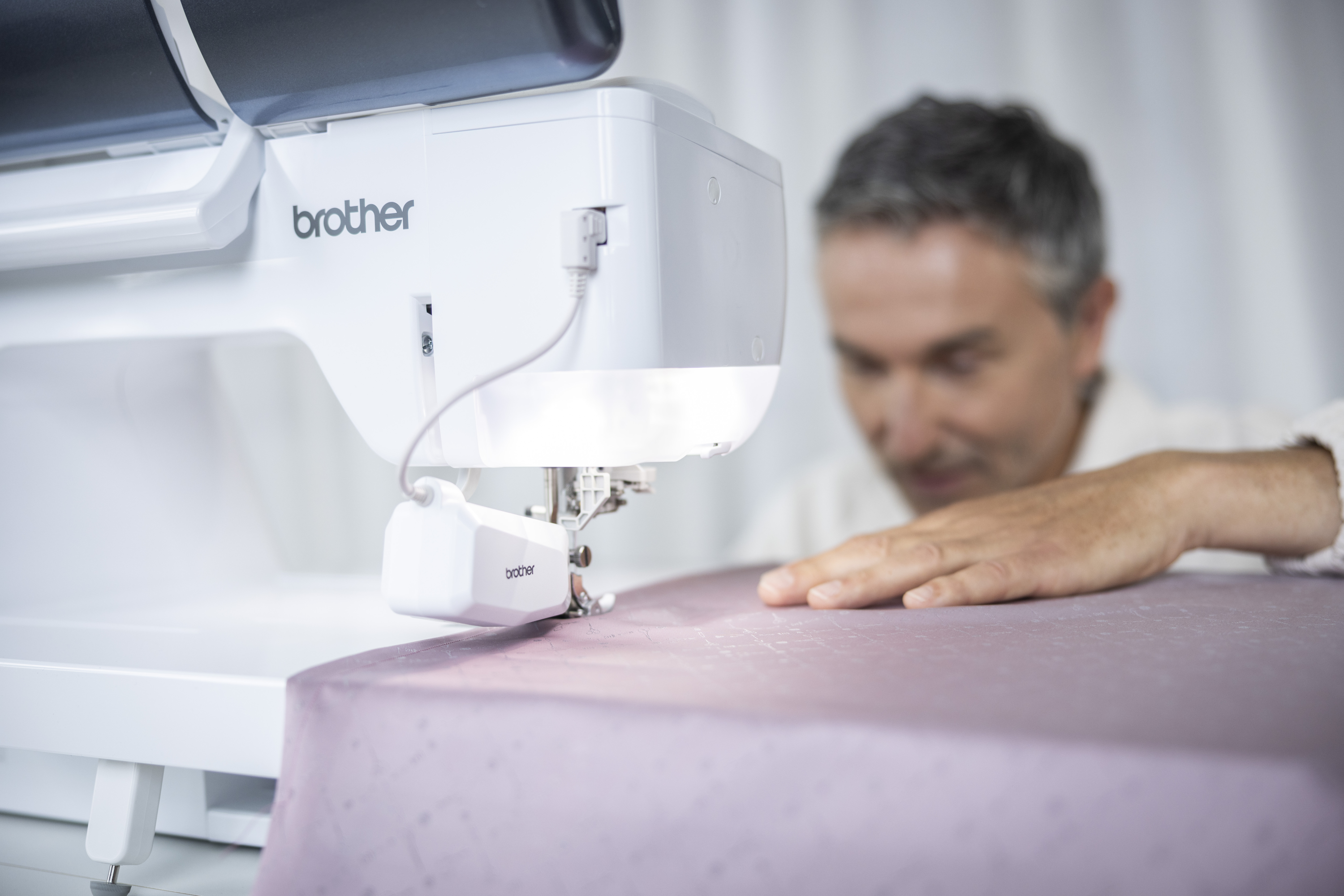 Person using a Brother sewing machine on a white background