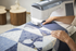 Person using a sewing machine on a quilt with wooden stools in the background