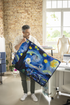 Man holding a colorful abstract quilt in an office setting