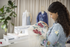 Woman holding a floral-patterned fabric in a sewing room.