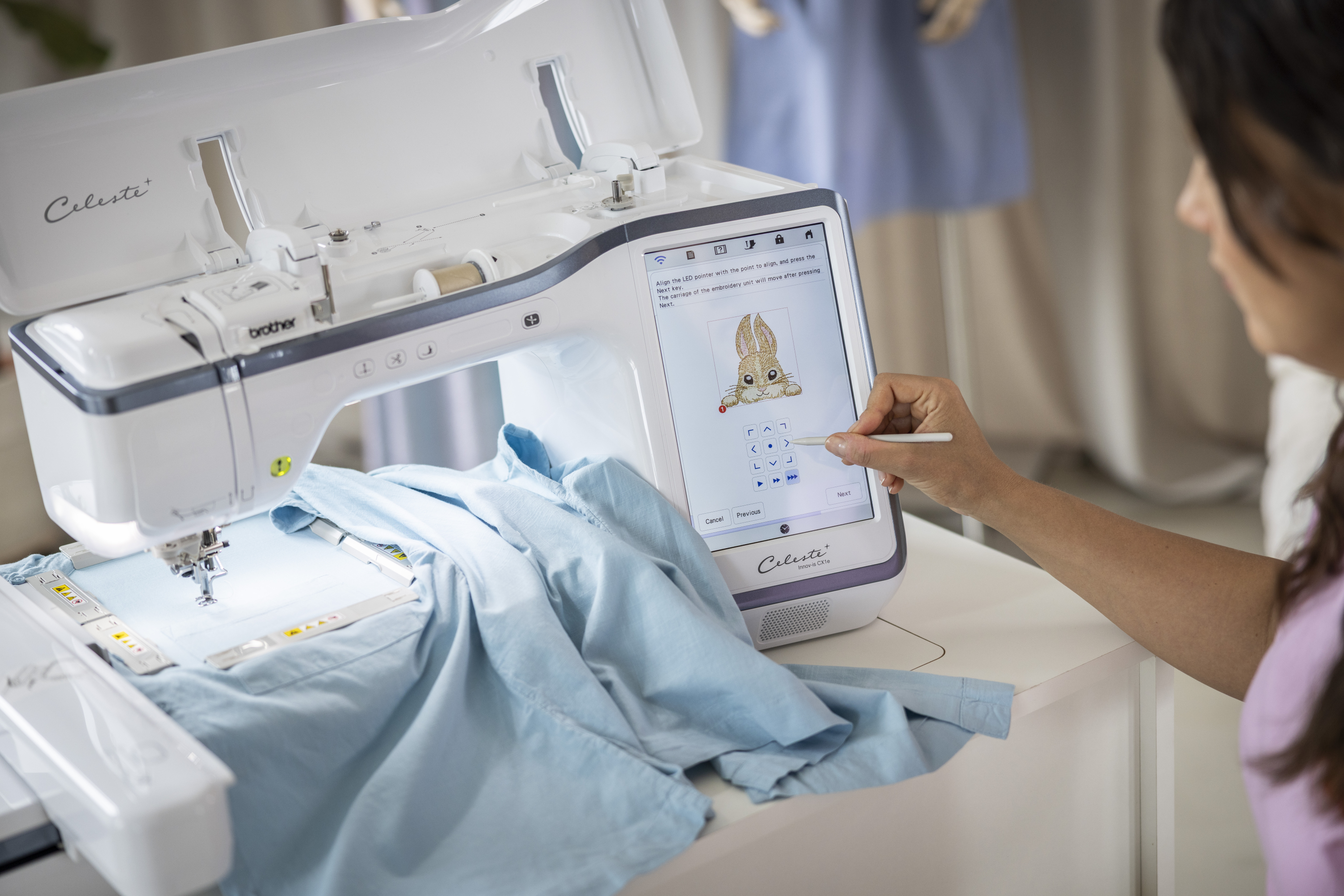 Person using a embroidery machine with a digital display on a table.