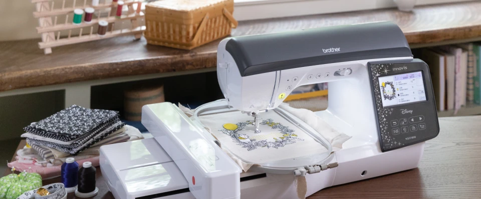 Brother sewing machine on a table with various fabrics and tools in the background