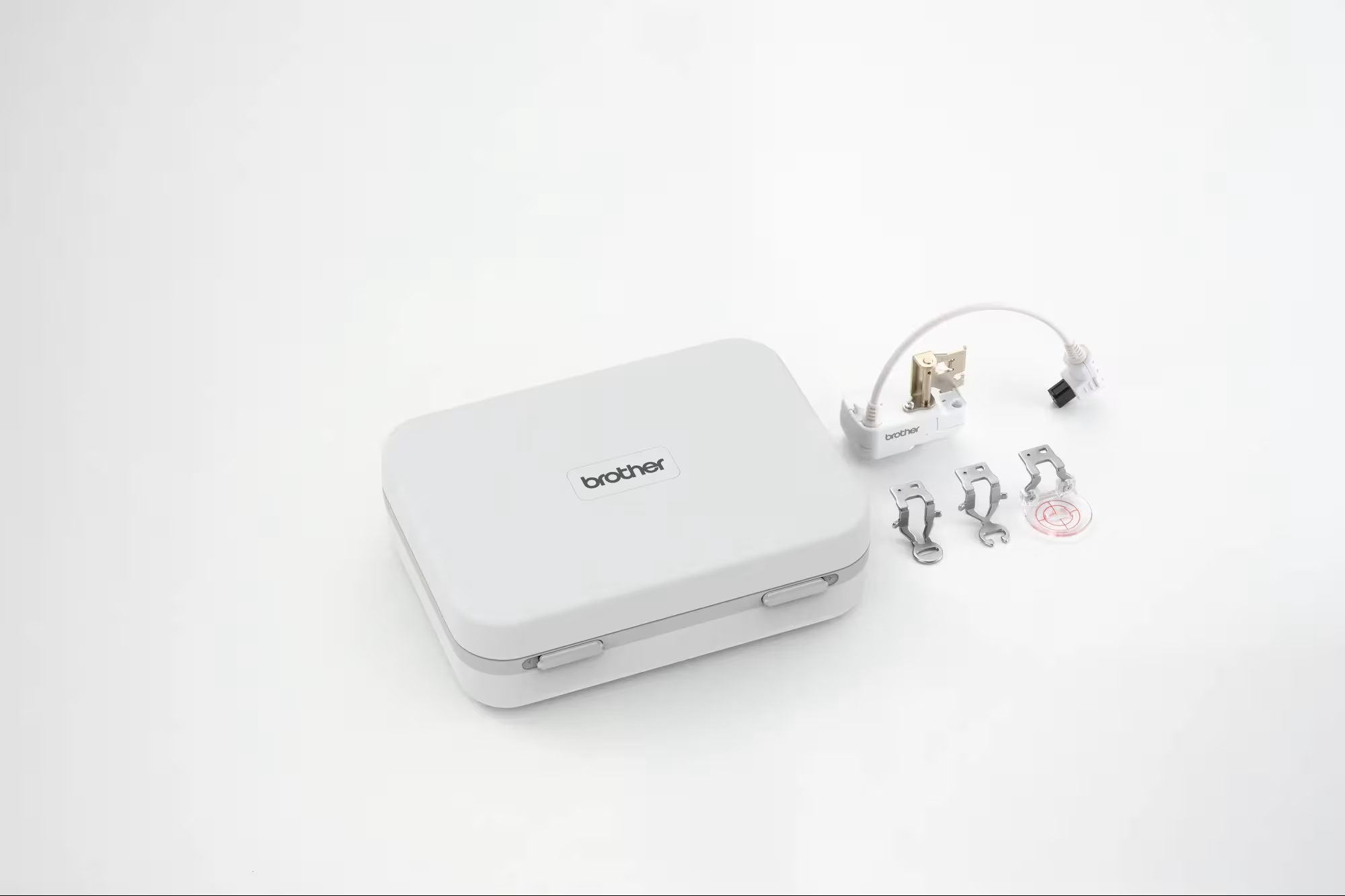 A Brother-branded stitch regulator with a small attached white cable and several small metal sewing feet photographed on a clean white background.
