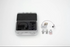 An open gray hard carrying case with black foam inserts, shown next to a small white and gray stitch regulator, three metal sewing feet, and a small round accessory on a clean white background.