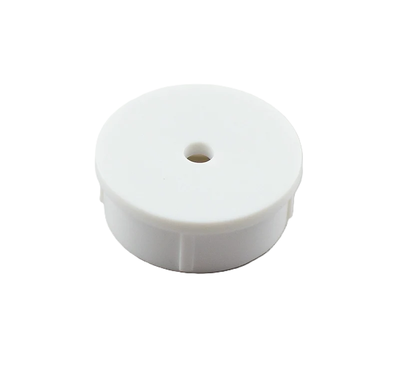 A small white plastic cylindrical cap or cover with a single central hole, shown on a plain white background.