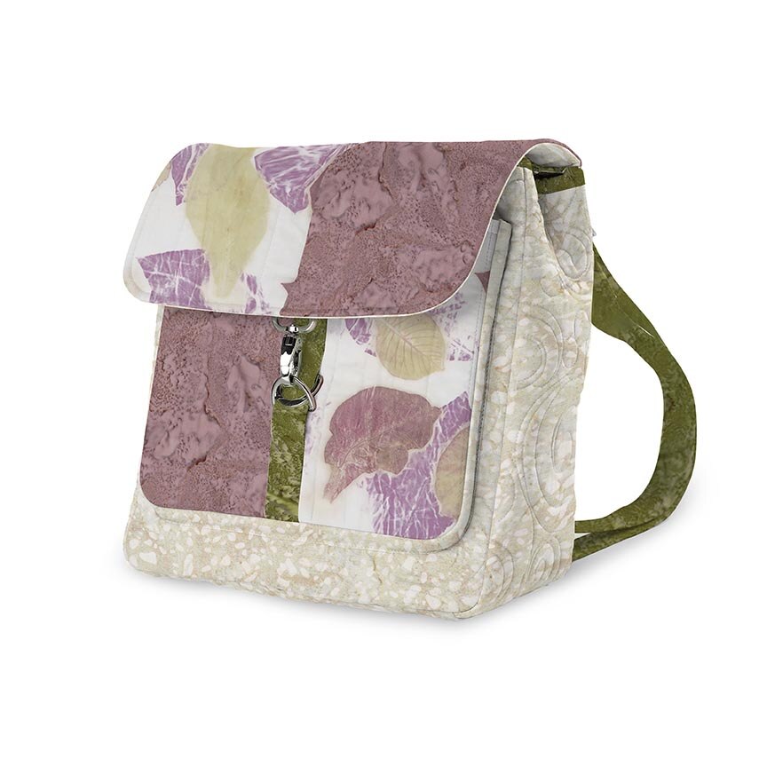 A quilted fabric crossbody bag featuring a floral patchwork design in dusty purple, olive green, and cream, with a zippered front pocket and a single shoulder strap.