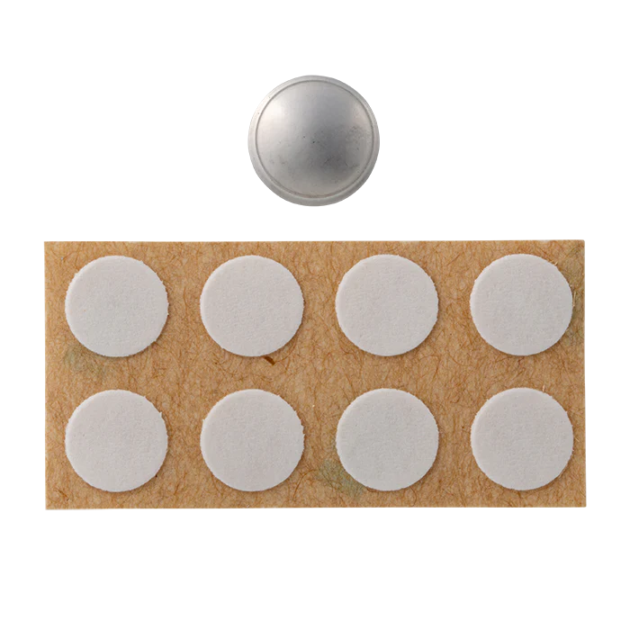 Set of white adhesive dots on a cardboard backing with a silver dome-shaped object above.